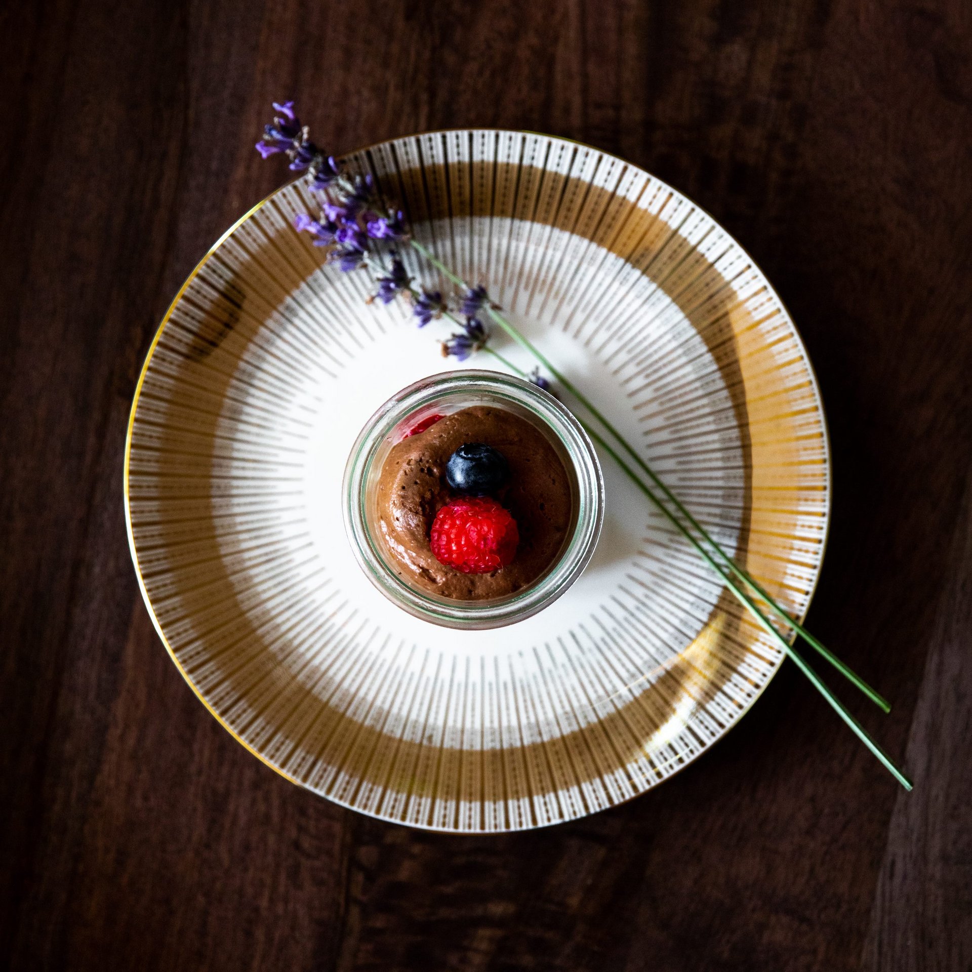 Elegantes Dessert-Erlebnis Dessert im Glas mit Beeren und Lavendel auf elegantem Teller präsentiert.