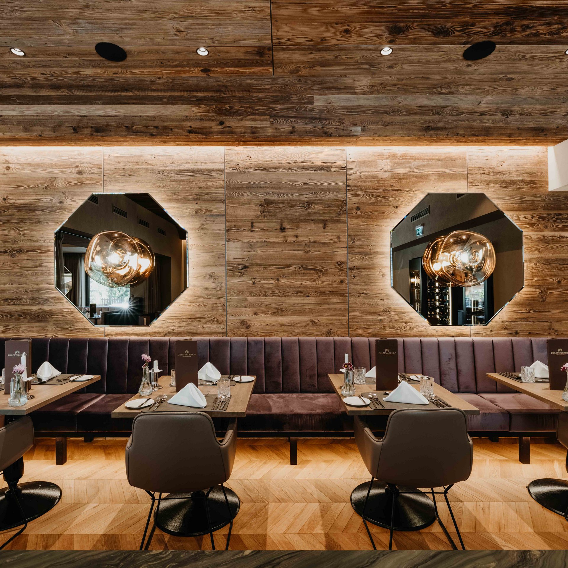 Elegantes Restaurantambiente Stilvolles Restaurant mit Holzwand, gemütlichen Sitzbänken und modernen Lampen